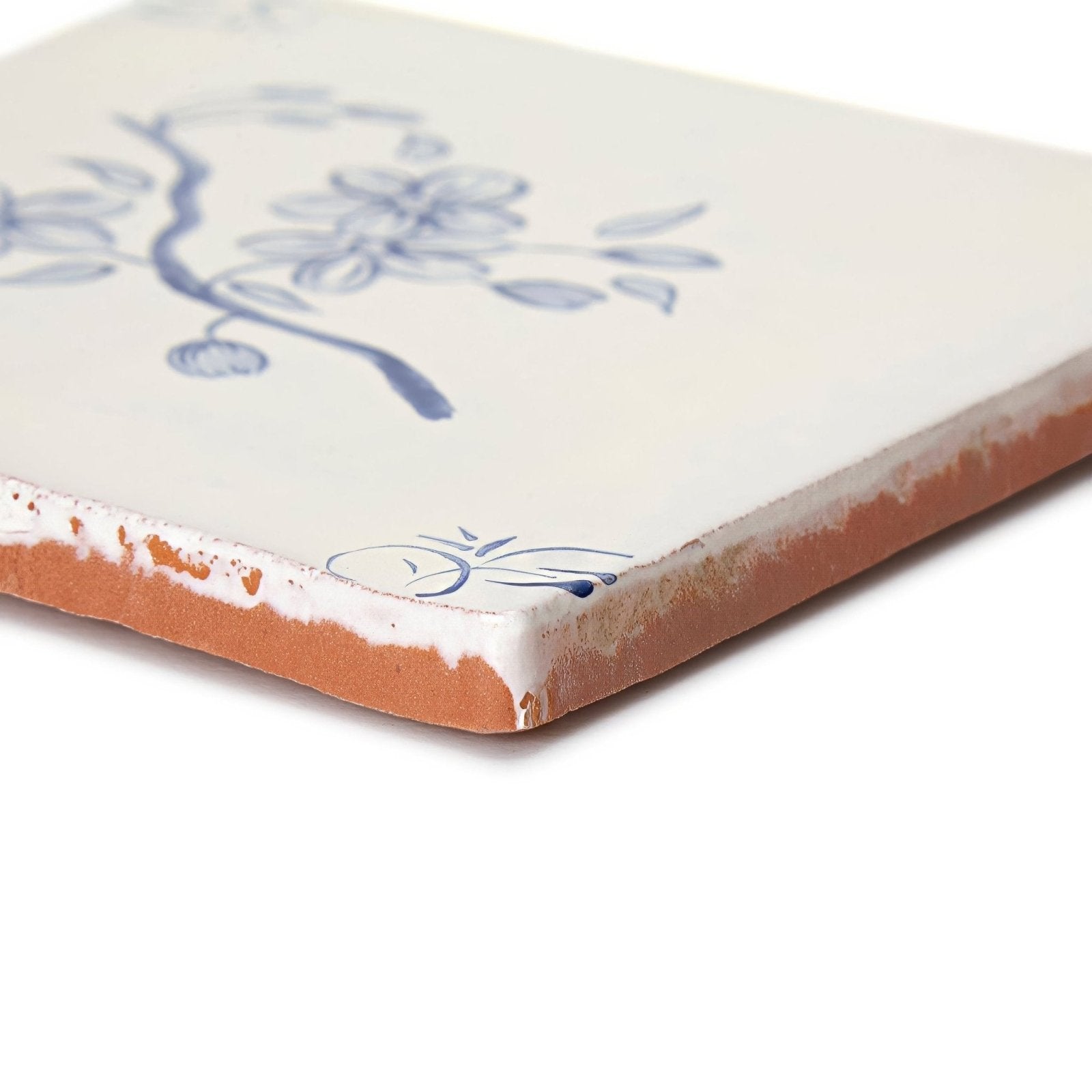 Cream-colored ceramic English delft blossom blue gloss tile with delicate blue floral design and exposed terracotta edge
