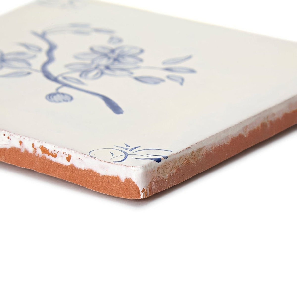 Cream-colored ceramic English delft blossom blue gloss tile with delicate blue floral design and exposed terracotta edge