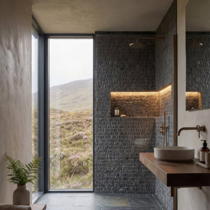 Enso Cobble Mosaic Strip Charcoal dark grey pebble mosaic in a bathroom setting with a modern white ceramic sink