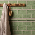 A beige waffle-weave half tile estuary towel hanging from a rustic wooden rack for bathroom use