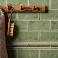 Half tile estuary green tiled wall with a rustic wooden hook rack featuring three natural toned pegs mounted