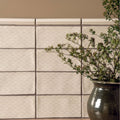 Cream-colored ceramic fabrique rosaline soft taupe tiles with subtle wave pattern arranged in grid on beige wall