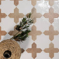 Woven wicker basket with a dark glass bottle nestled inside featuring fez porcelain cross cotto design