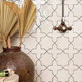 A rustic brown porcelain vase holding dried golden palm fronds featured in fez porcelain cross white collection