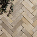 Beige stone clay pavers arranged in a herringbone pattern featuring the flanders buff tumbled finish