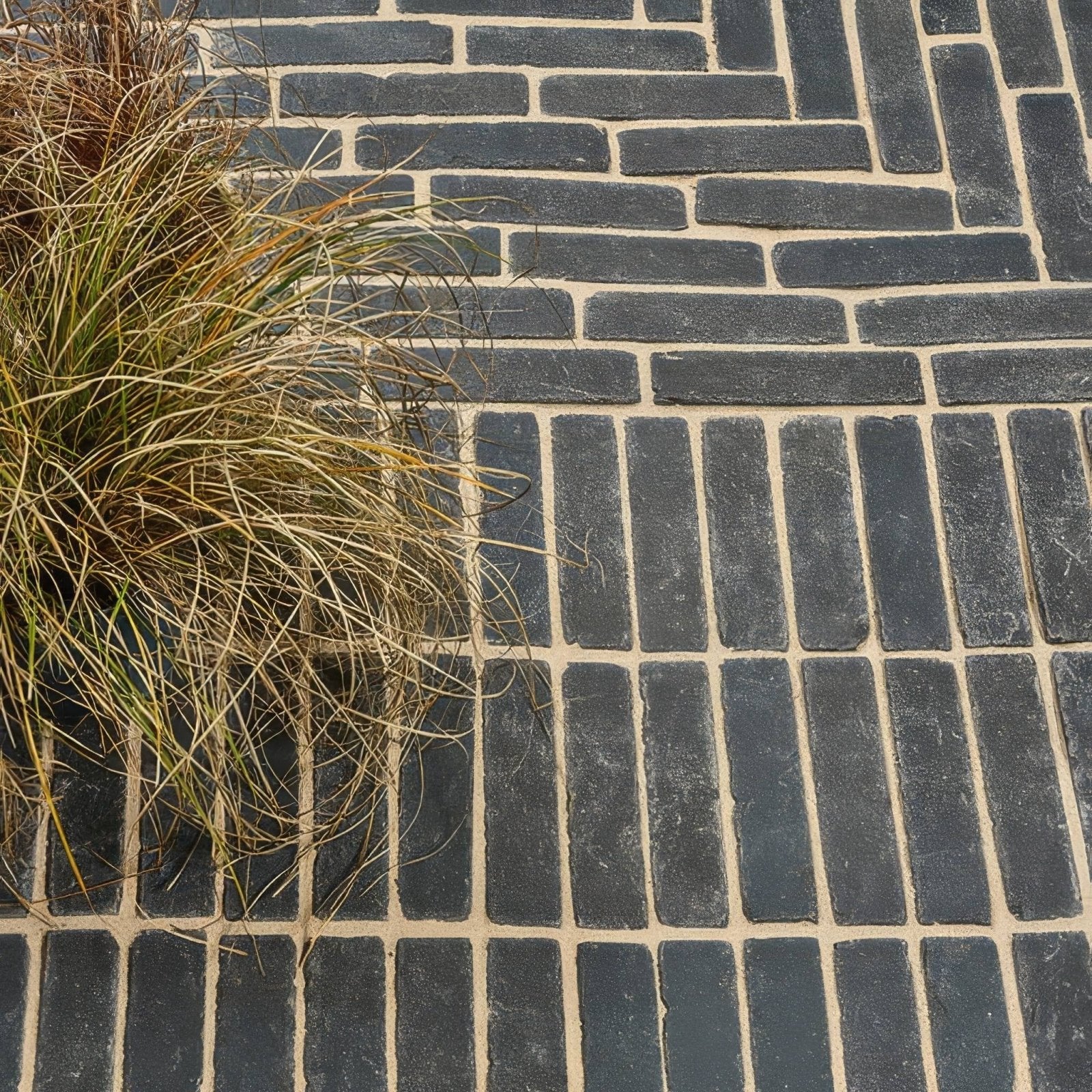 Dark gray flanders charcoal tumbled clay pavers arranged in a herringbone pattern with light beige mortar