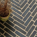 Dark gray rectangular flanders charcoal tumbled clay pavers arranged in a herringbone pattern