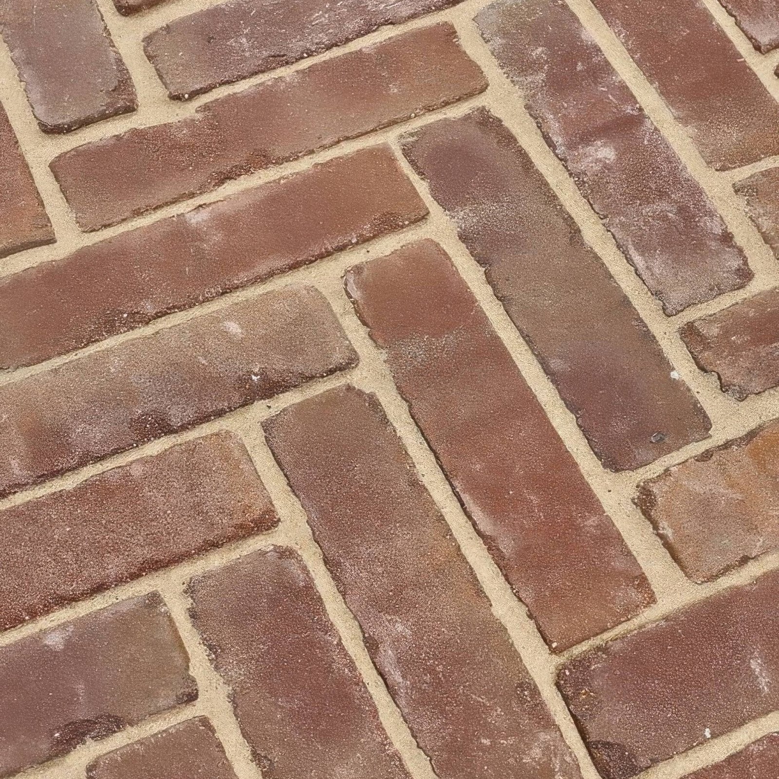 Reddish-brown flanders warm russet tumbled clay pavers with textured surface laid in a herringbone pattern with beige mortar