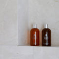 Folio Marble Honed Finish 61 x 40.6cm off-white marble tiles with amber bath bottles on a shelf