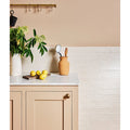 Fondant ceramic ecru jar with rounded body and narrow neck holding a wooden spoon and silver ladle