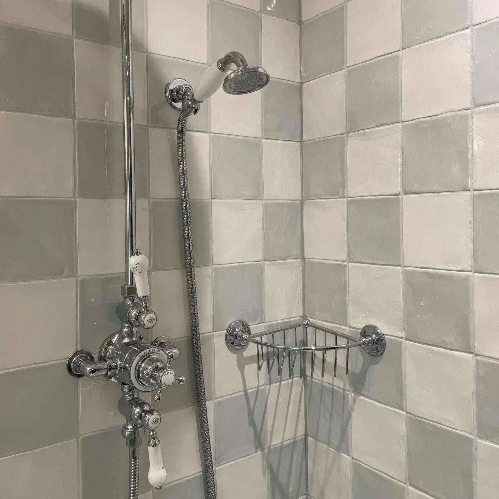 Chrome-finished shower fixture with white ceramic handle and spout mounted on light gray forecast arran square glazed tile