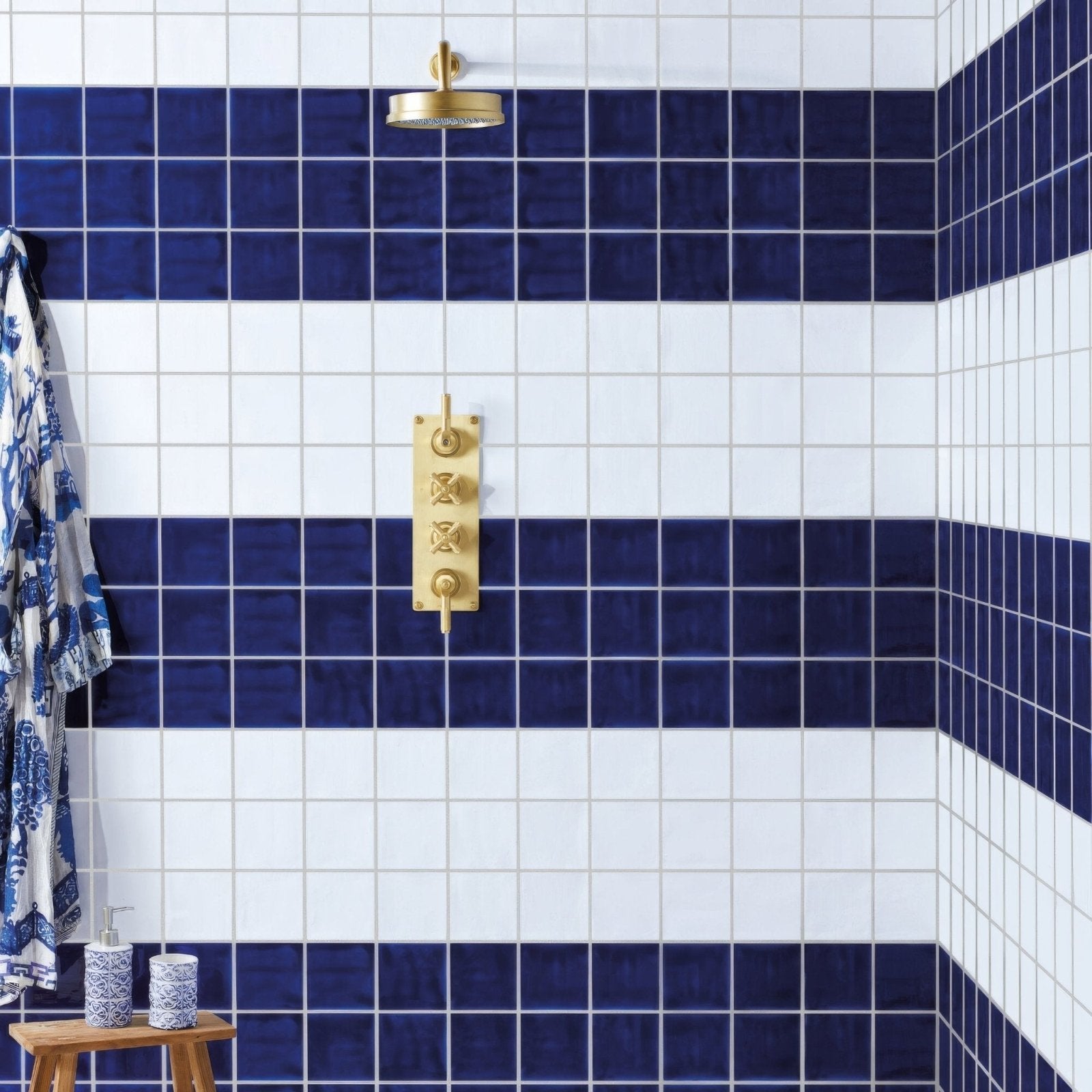 Gold-toned showerhead with brushed metallic finish and circular design shown with forecast wight rectangle glazed tile