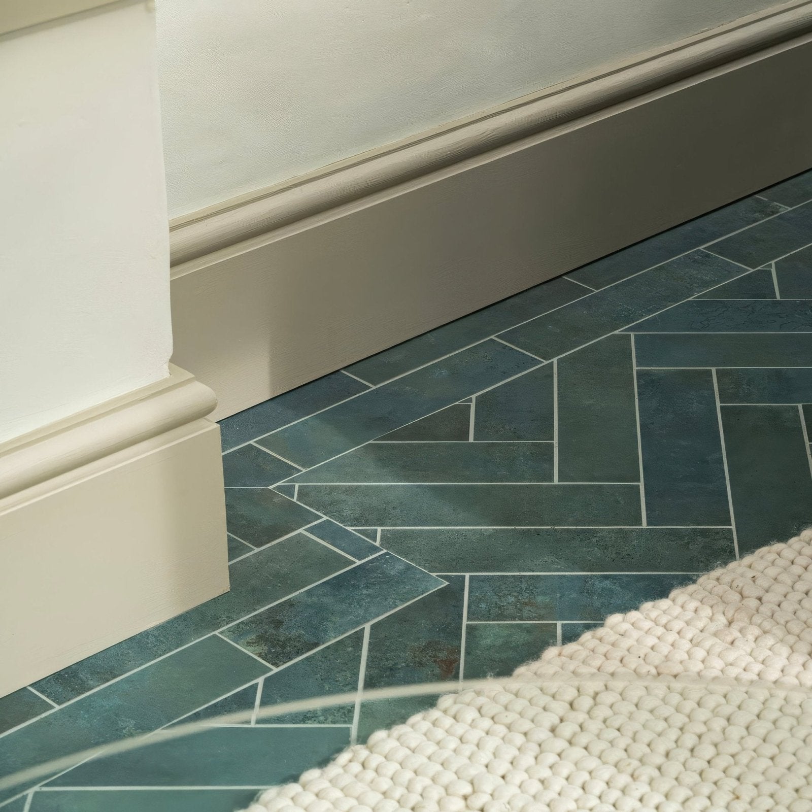 Dark teal forged emerald porcelain floor tile with herringbone pattern and subtle white grout lines