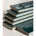 Stacked rectangular foundry novo porcelain tiles with glossy deep green glaze and textured light gray concrete edges