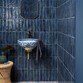 Foundry porcelain blue sink in blue and white porcelain with intricate floral patterns on brass fixture against dark blue tiles