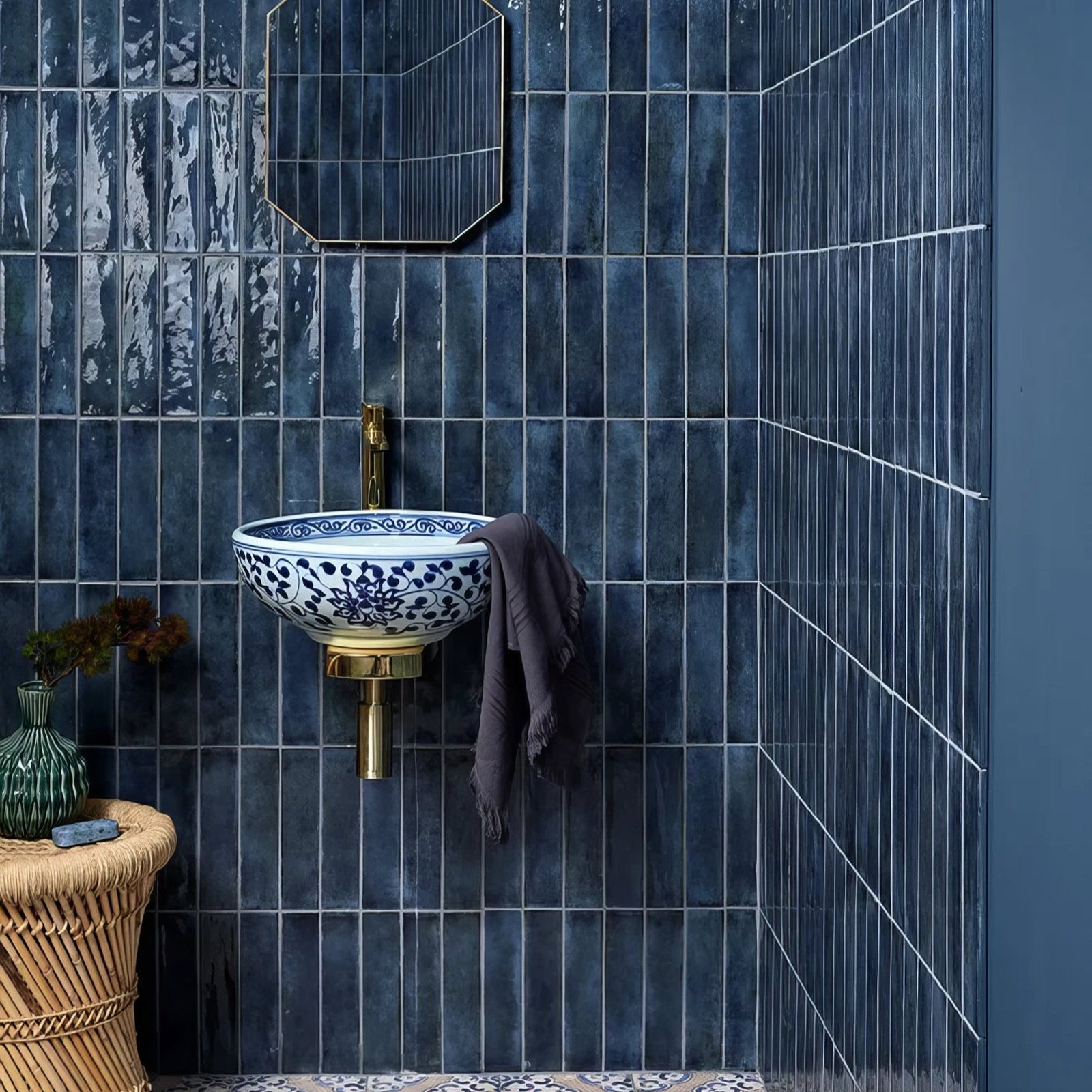 Foundry porcelain blue sink in blue and white porcelain with intricate floral patterns on brass fixture against dark blue tiles