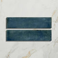 Two rectangular navy blue foundry porcelain blue ceramic tiles with textured matte finish on white marble surface