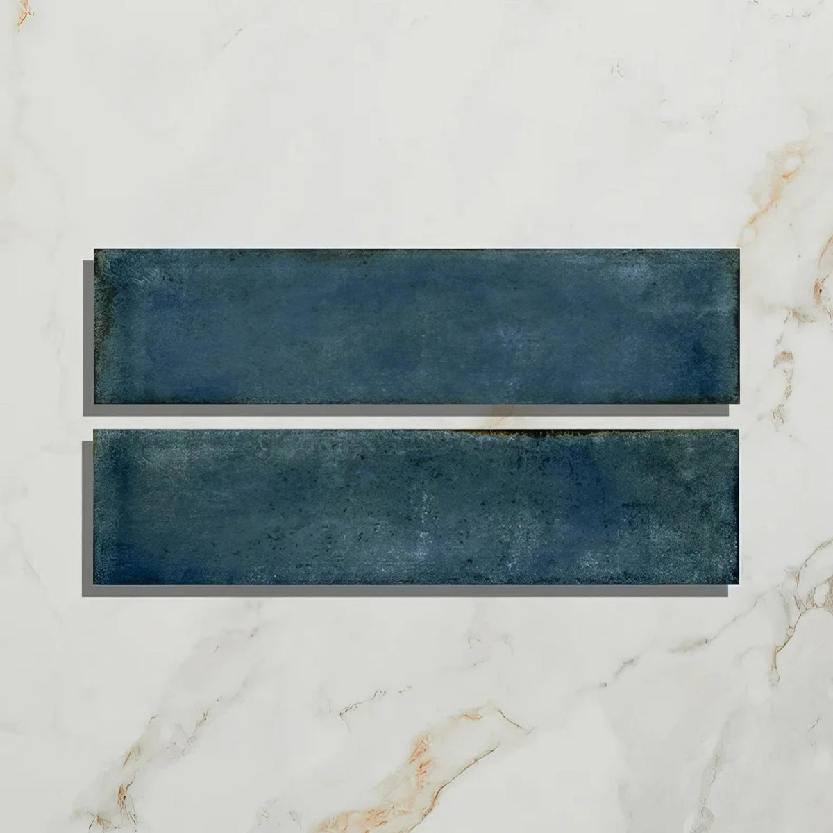 Two rectangular navy blue foundry porcelain blue ceramic tiles with textured matte finish on white marble surface