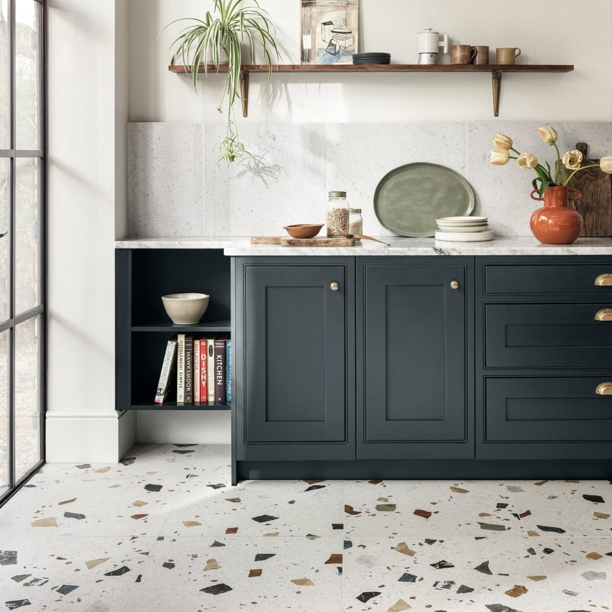 Dark blue kitchen cabinets with gold-tone handles and white marble countertop featuring frammento multi terrazzo effect porcelain tile