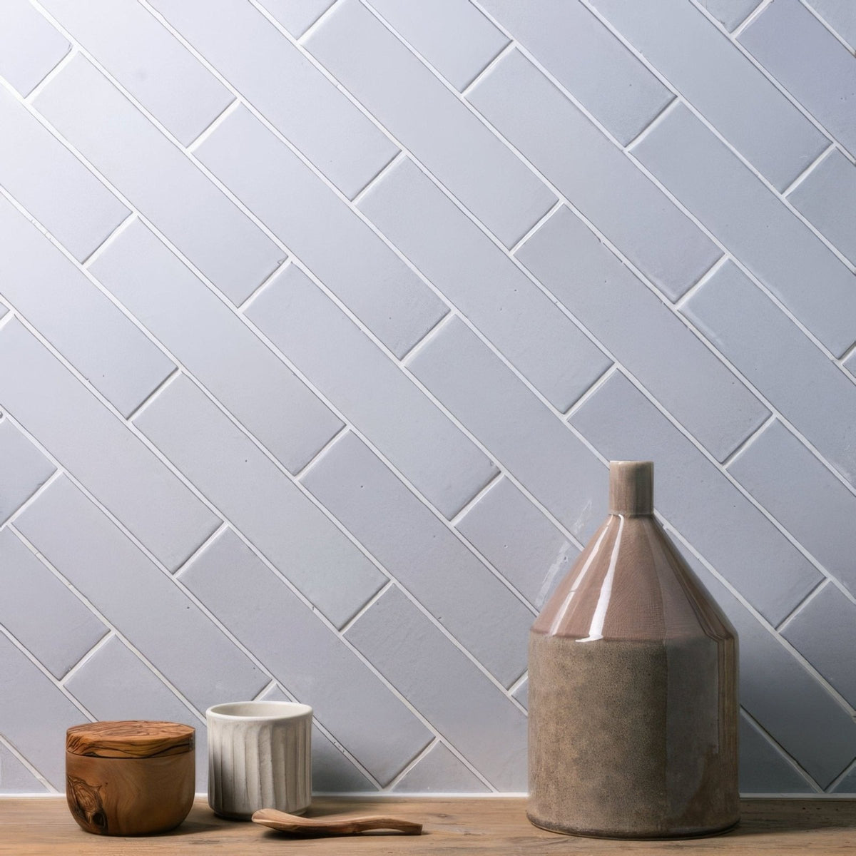 A matte-finished taupe ceramic vase with a flared neck and tapered body displayed on frost smooth brick tile
