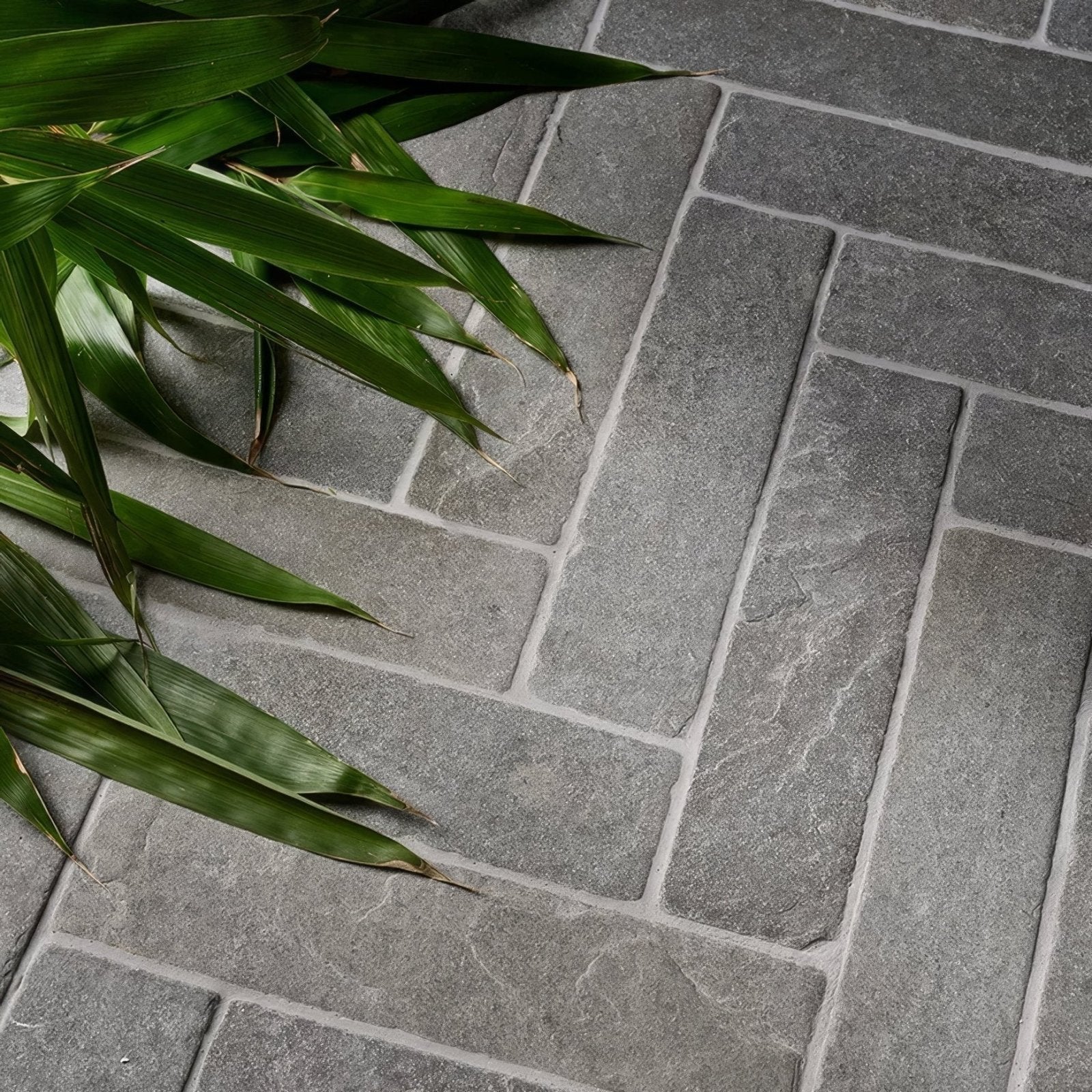 Gray stone tiles in a herringbone pattern with natural veining and subtle texture in galway limestone seasoned parquet