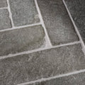 Dark gray rectangular seasoned parquet stone tiles with rough textured surface and white grout lines made of galway limestone