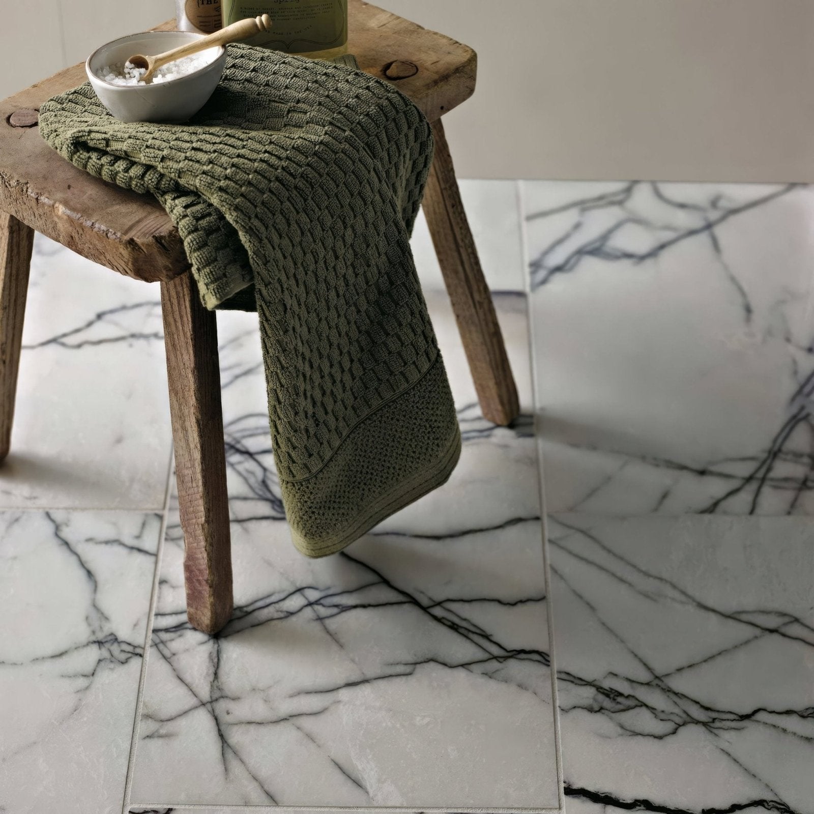 Georgica Pond Diamond Sawn Edge Polished white marble tiles with an olive green towel on a stool