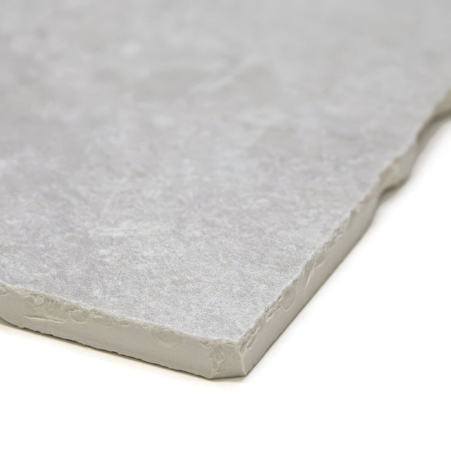Giotto chalk gray stone tile with textured natural surface and irregularly cut edges for flooring or walls