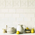 A matte white ceramic pitcher with a curved handle and speckled texture for giralda cascara cream tile collection