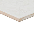 White ceramic giralda hielo decor tile with subtle embossed floral design and beige-colored edge