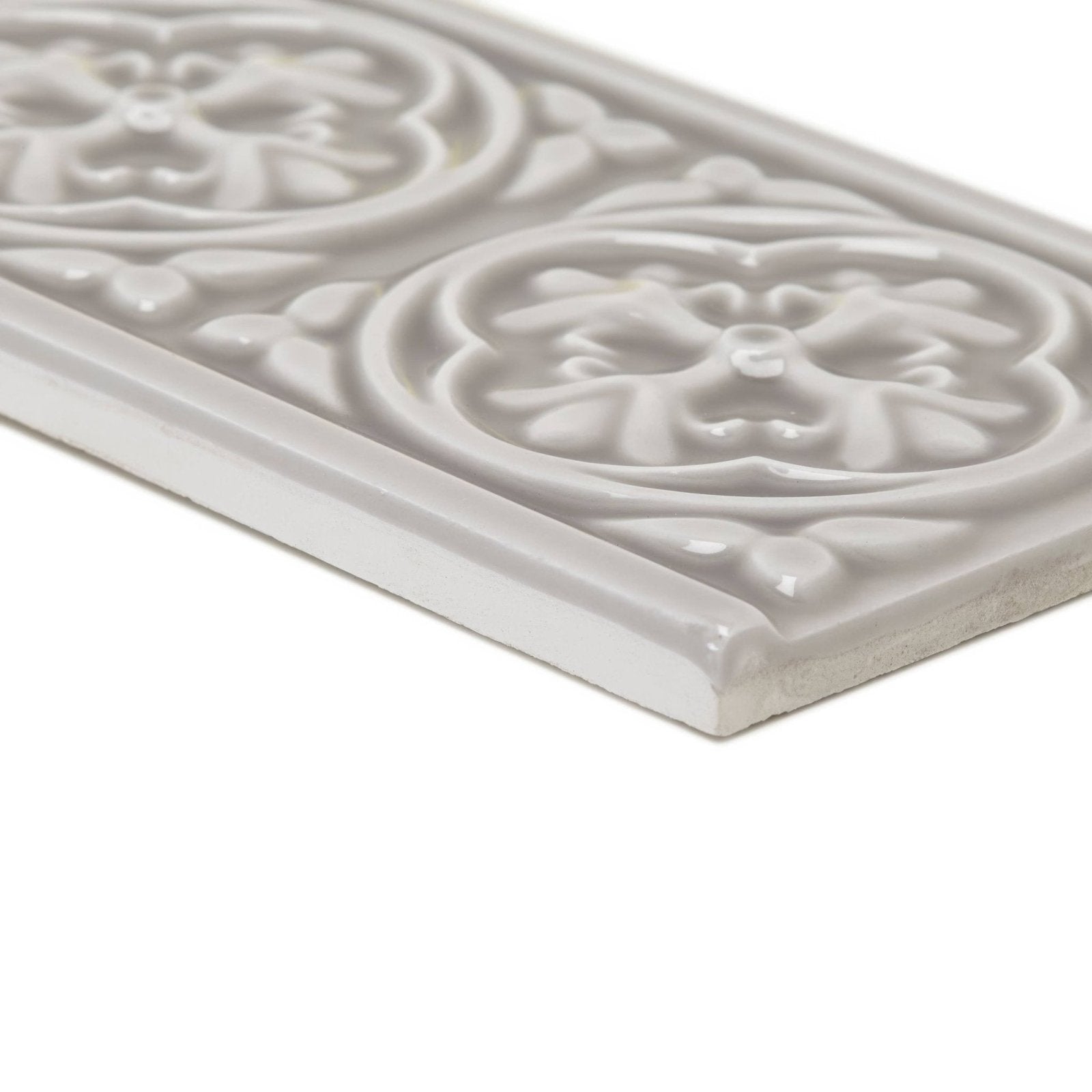 A rectangular off-white ceramic giralda niebla grey border tile with raised floral and leaf patterns