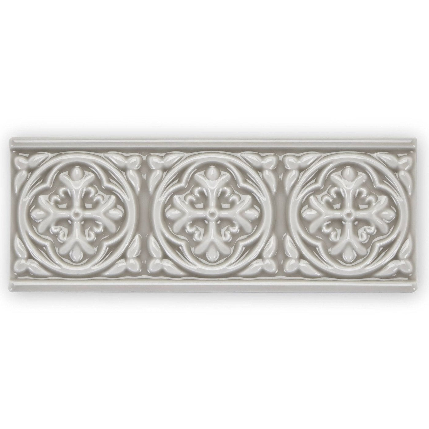 A rectangular off-white ceramic tile giralda niebla grey border with three raised floral medallions and leafy patterns