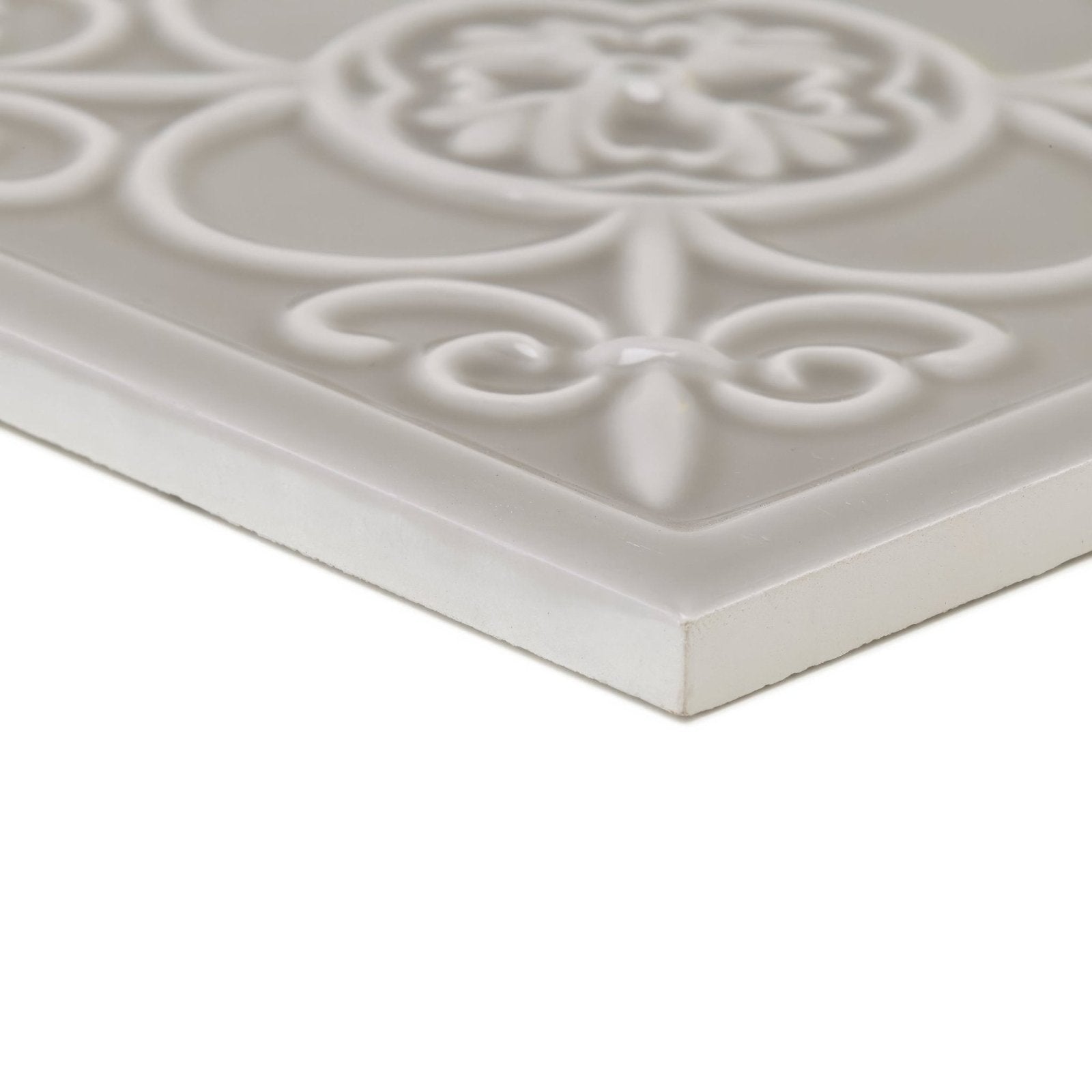 A white ceramic Giralda Niebla Grey decor tile with embossed floral and scrollwork design