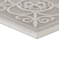 A white ceramic Giralda Niebla Grey decor tile with embossed floral and scrollwork design