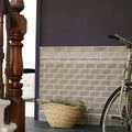 A woven natural fiber basket filled with dried greenery on the floor beside giralda niebla grey tile flooring