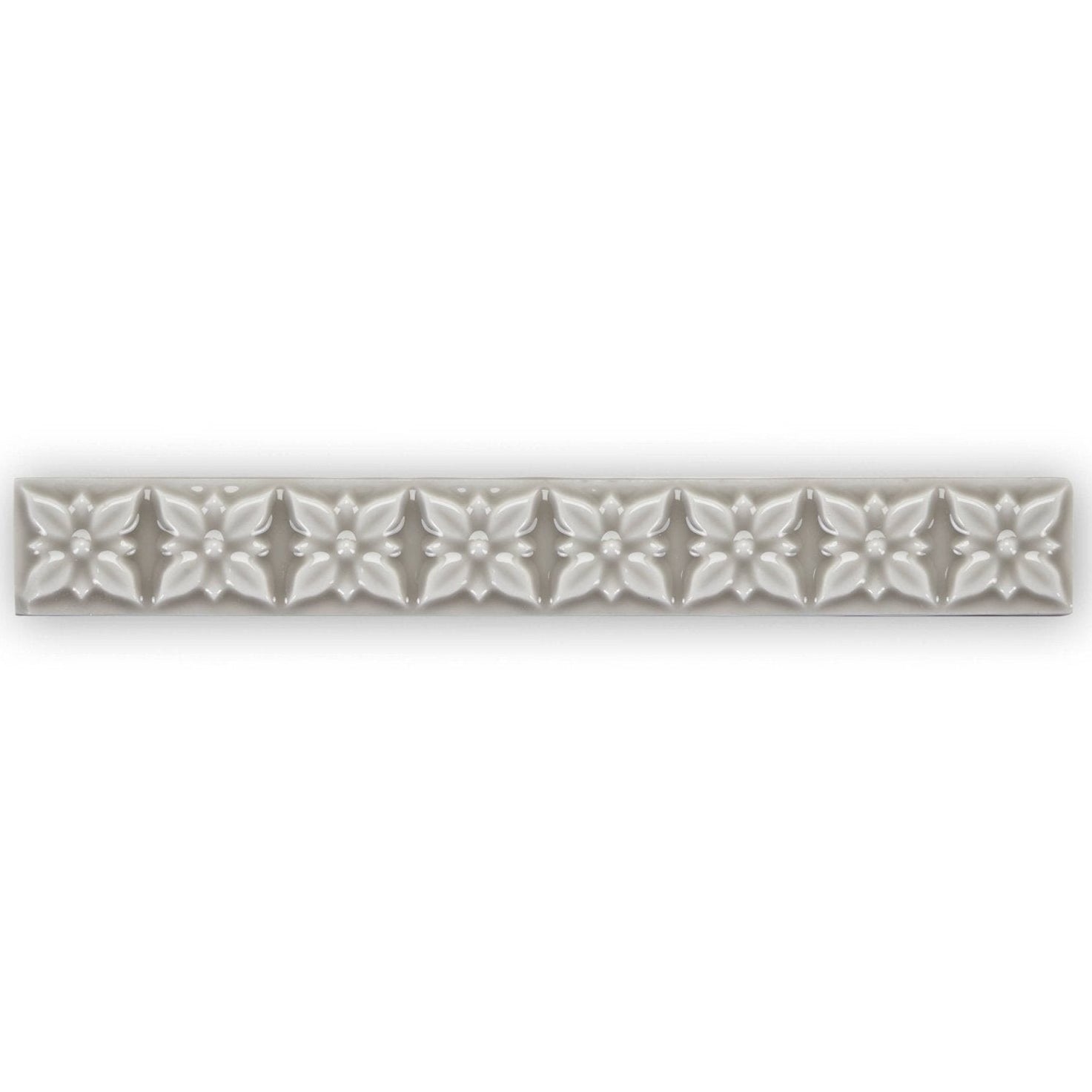 Giralda Niebla Grey Trim sleek off-white ceramic tile strip with embossed five-petaled floral pattern and central dots