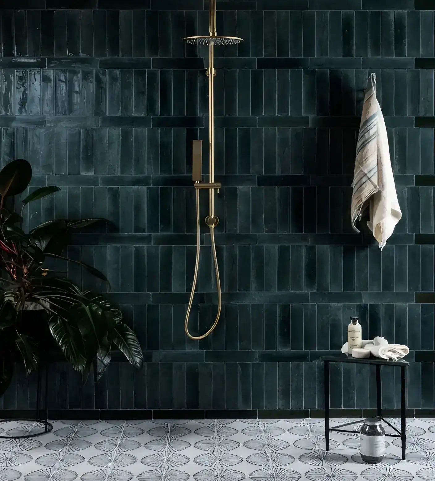 Gold-toned showerhead with a rain-style spray and matching handheld hose against dark green tiled wall