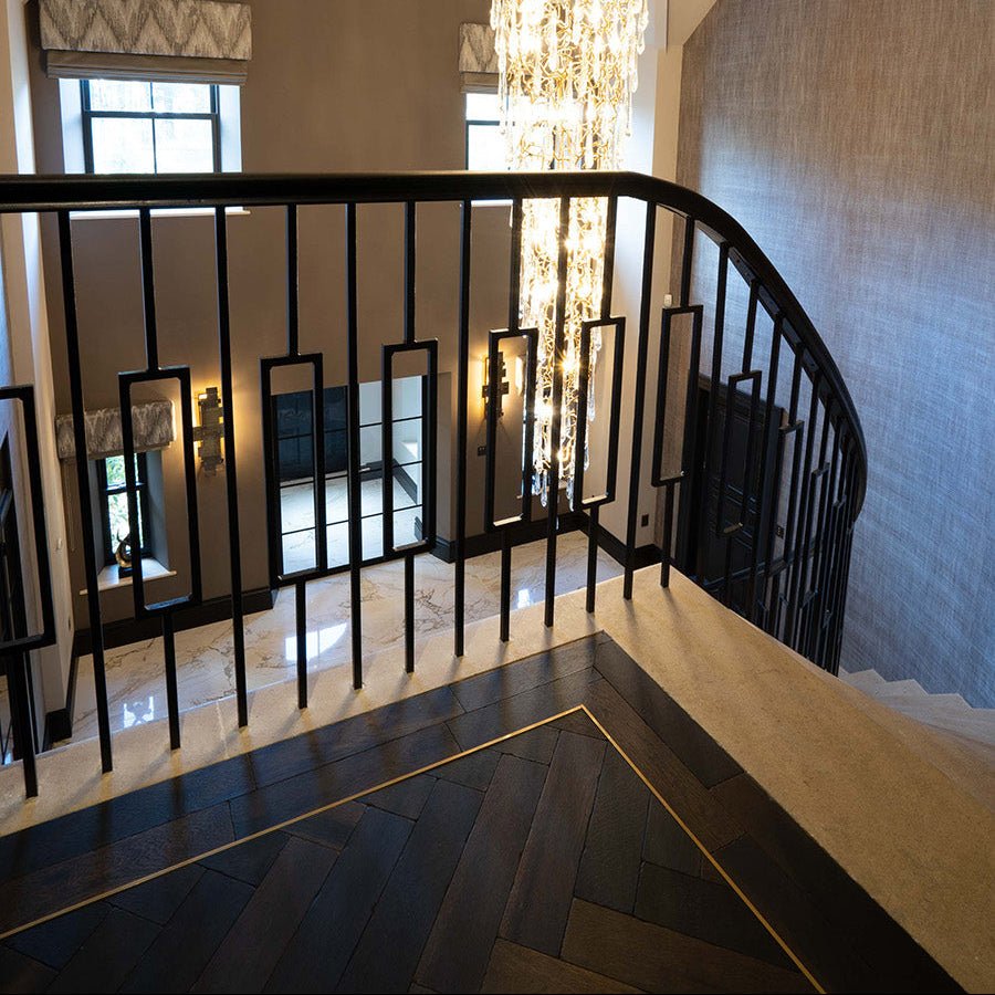 Black wrought iron staircase railing with geometric rectangular cutouts in goodrich charred oak finish