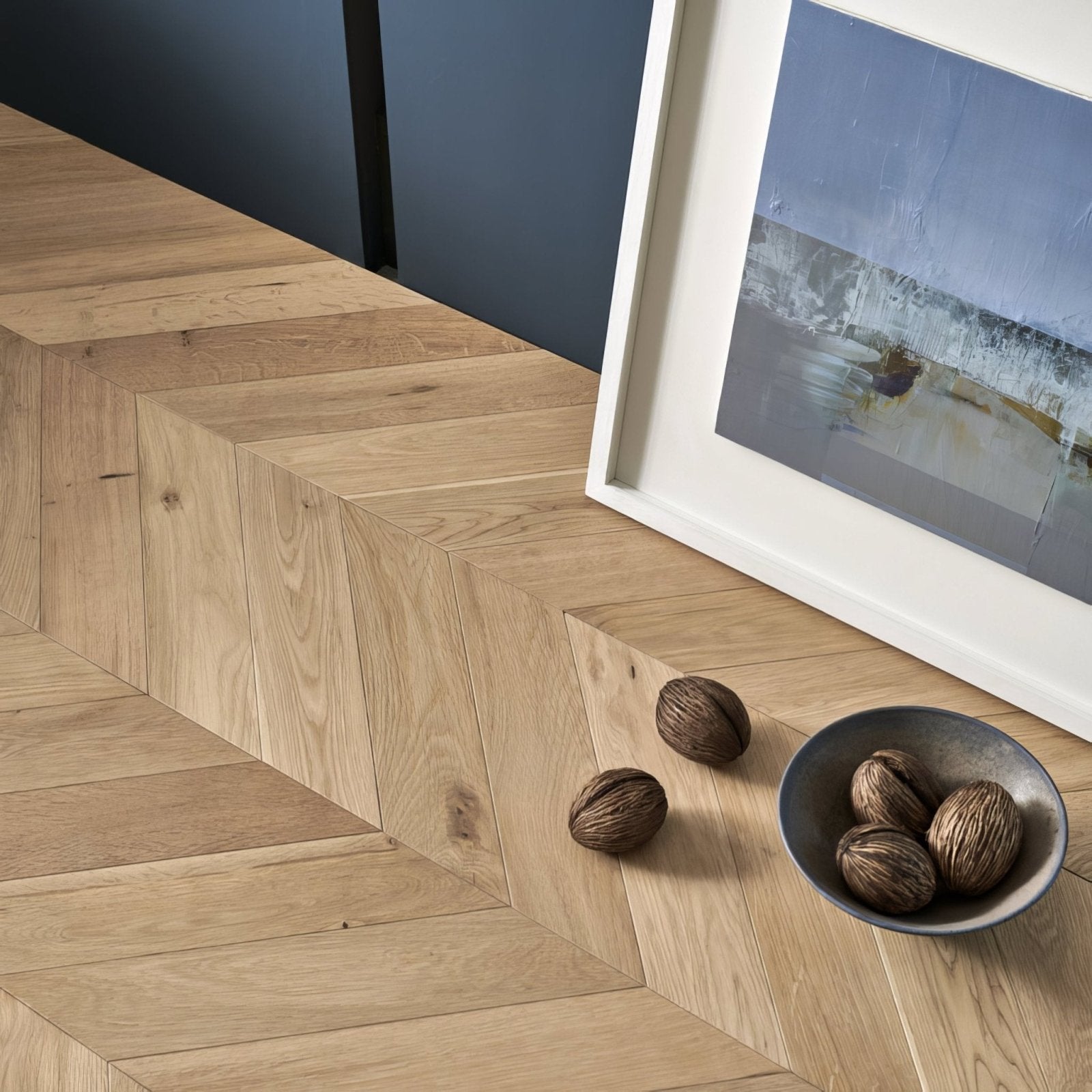 A sleek matte gray ceramic bowl holding striped raw oak chevron walnuts from goodrich