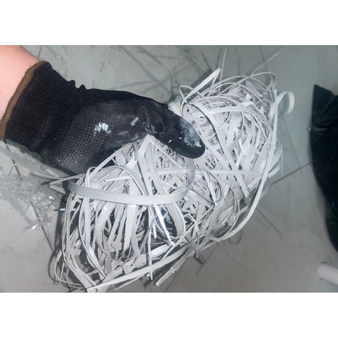 A tangled mass of white shredded paper strips held in a black glove for use with gopoxy epoxy grout applications