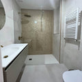 The gravity aluminium hexagon gold mosaic tiles clad a shower wall with brass fixtures and a glass enclosure