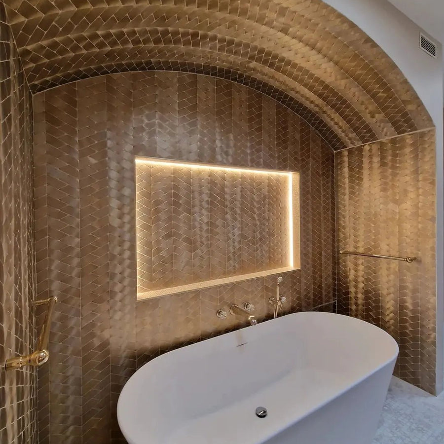 Gold-hued gravity aluminium trace gold mosaic tile wall with built-in illuminated mirror and freestanding white bathtub