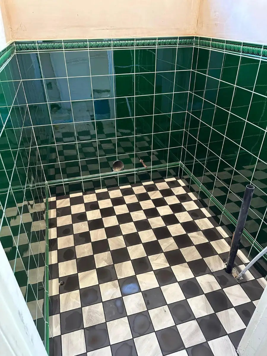 Green tiled walls with a black and white checkerboard floor in a finished interior.