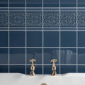 Deep blue glossy ceramic Grosvenor On Ascot blue tiles with ornate white border and gold-finished faucets