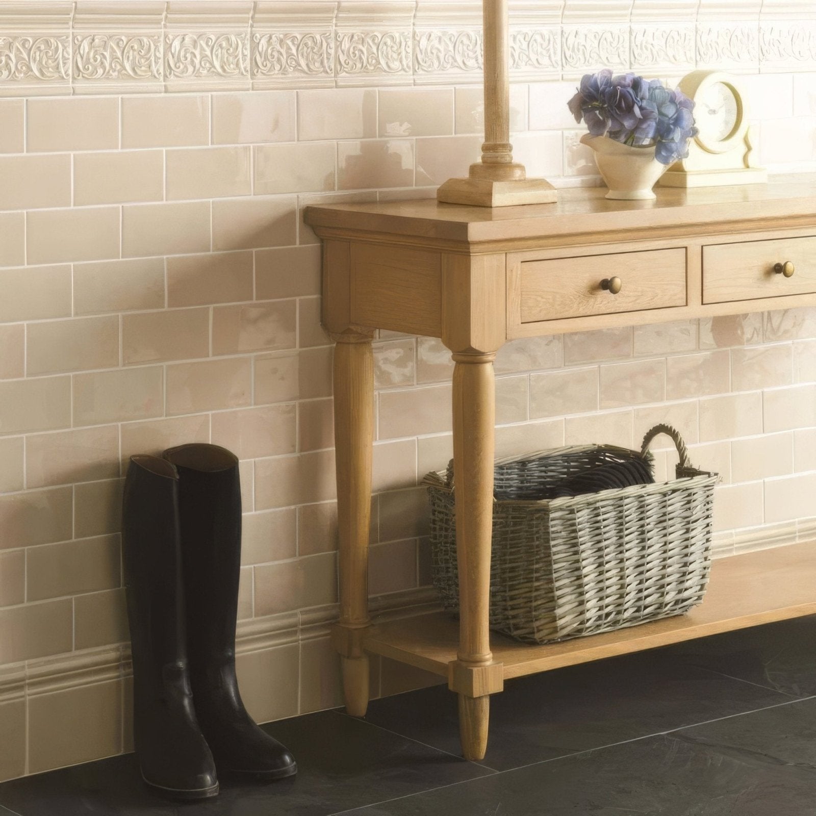 A pair of sleek black leather knee-high Hadleigh Chelsea boots standing upright against a tiled wall