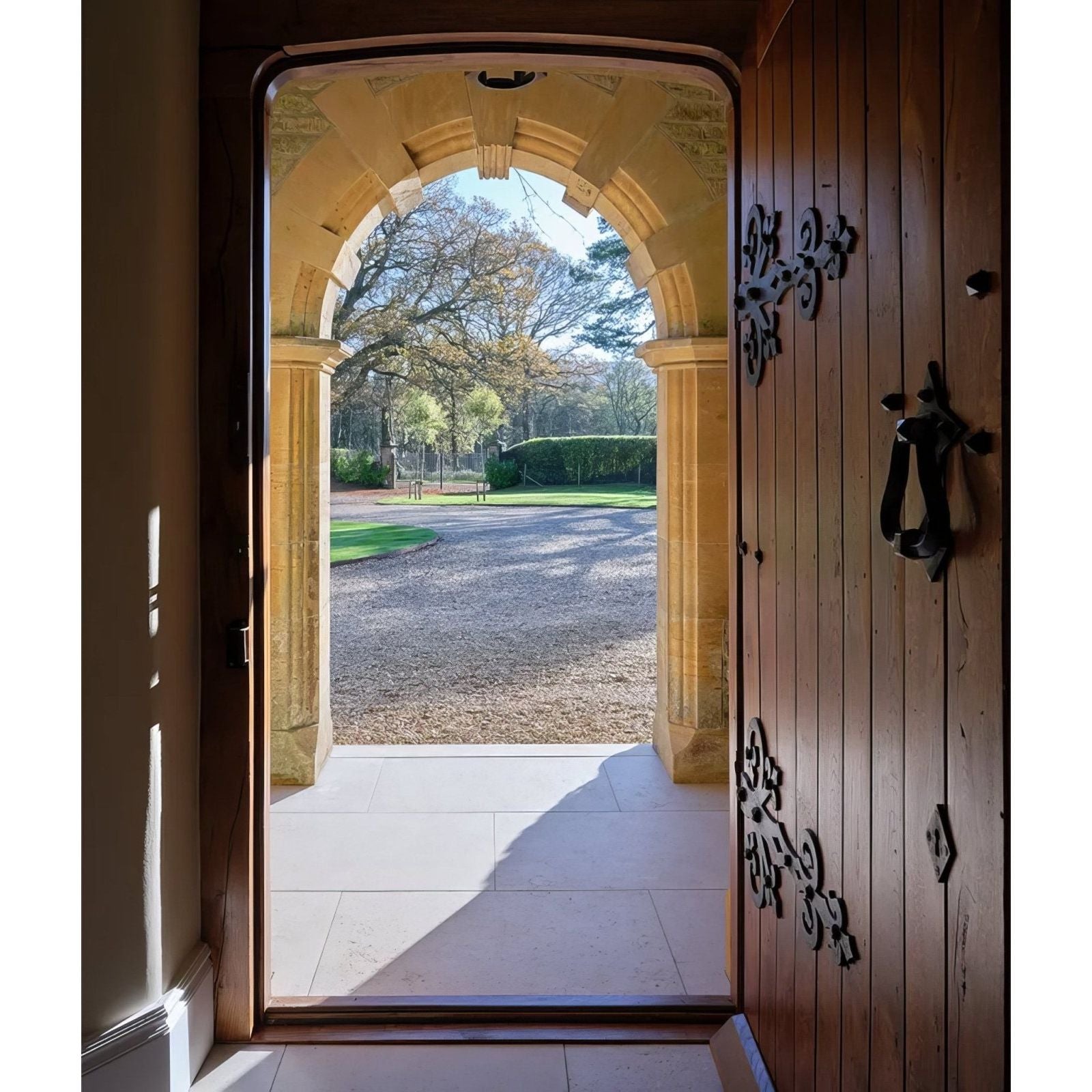 A rich dark wood door with ornate black metal hardware and decorative floral motifs in wychwood limestone velvet finish