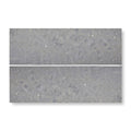 Two rectangular gray terrazzo tiles with a speckled textured surface from hampton bays 10 x 30cm honed collection