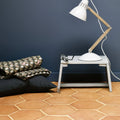 White metal desk lamp with wooden articulated arm featured alongside handmade classic terracotta hexagonal tile