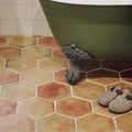Dark green clawfoot bathtub with ornate metal feet paired with handmade classic terracotta hexagonal tile flooring