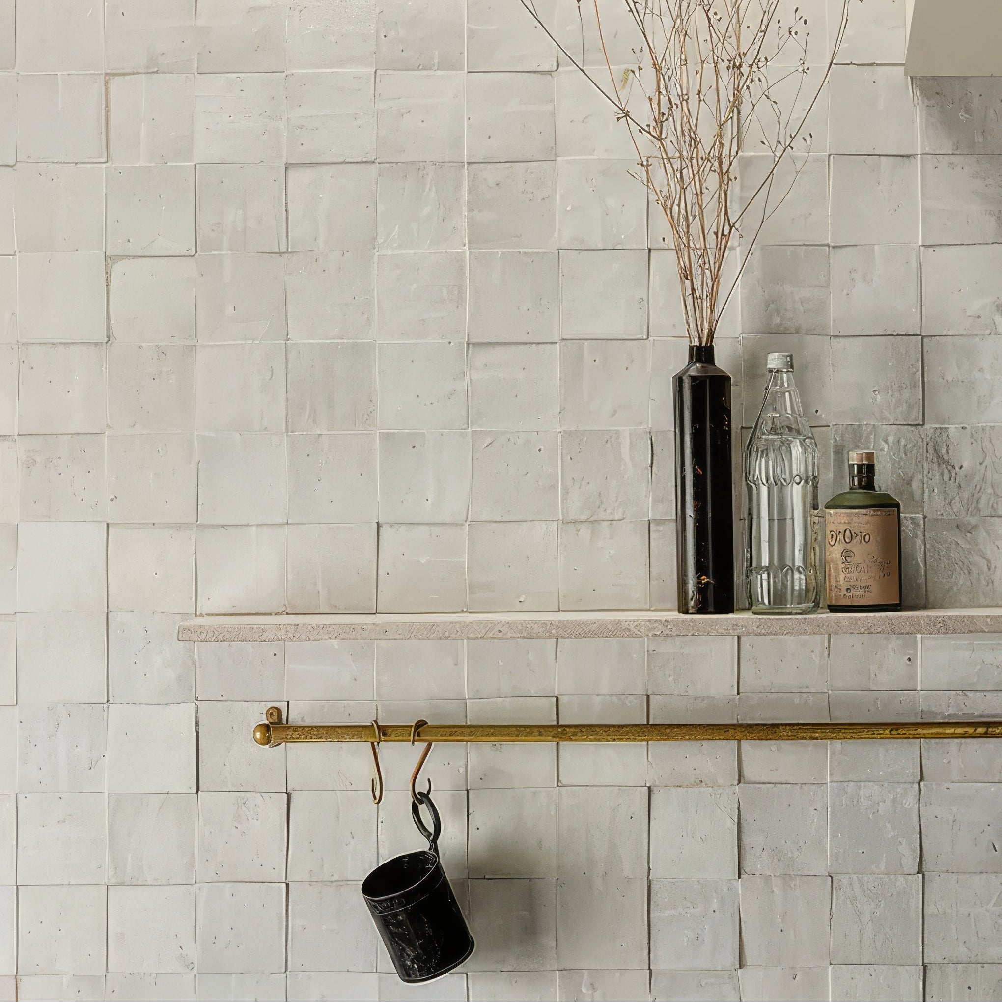 Tile wall with a shelf holding decorative items and a cup with a hook.